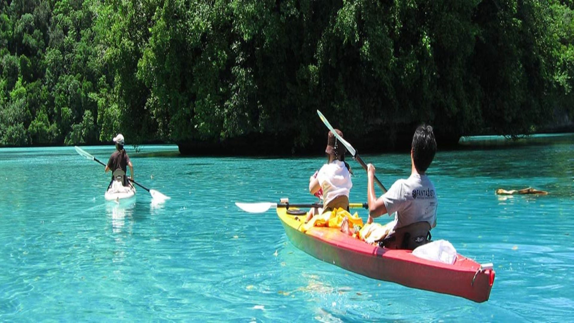 A Group Of People Riding On The Back Of A Boat In The Water